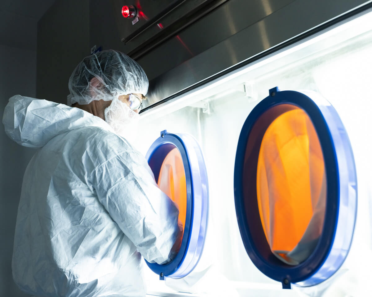 One of Gannet BioChem's cGMP manufacturing team members working with a glove box
